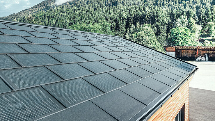 PREFA Solardachplatte in großer Ausführung kombiniert mit der Dachplatte R.16 in Schwarz, Kastenrinne und Lärchenholz-Fassade