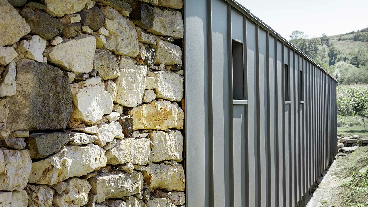 Moderne Kombination von PREFA Fassadenpaneelen und einer alten Hausmauer aus Stein
