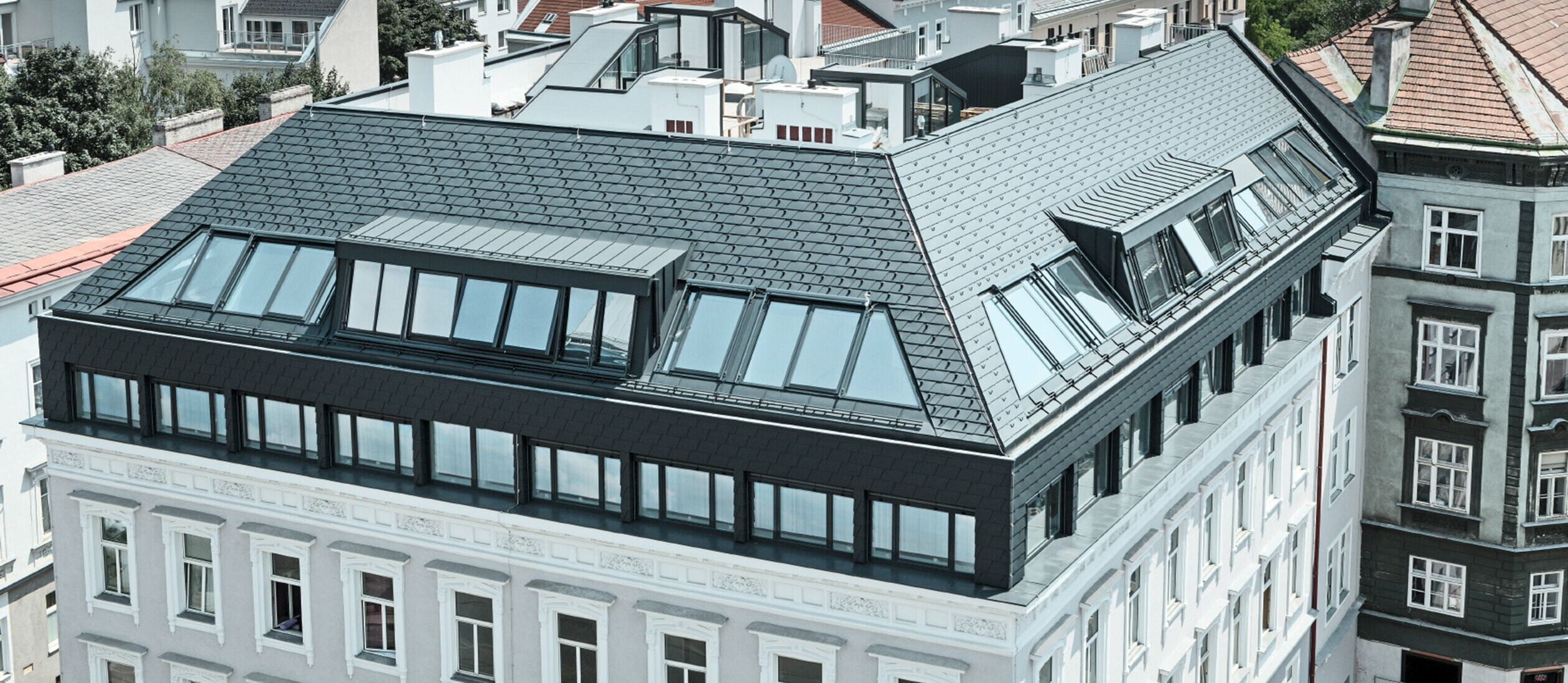 Dachgeschoßausbau eines Wohnhauses in Wien Mariahilf, das Dachgeschoß wurde mit Penthouse Wohnungen ausgebaut; Das Dach wurde mit PREFA Dachschindeln in Anthrazit verkleidet.