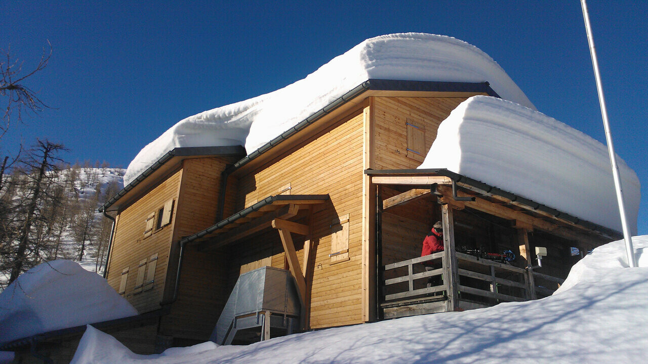 Hütte Capanna Buffalora mit mehreren Zentimetern Schnee auf dem Dach. 