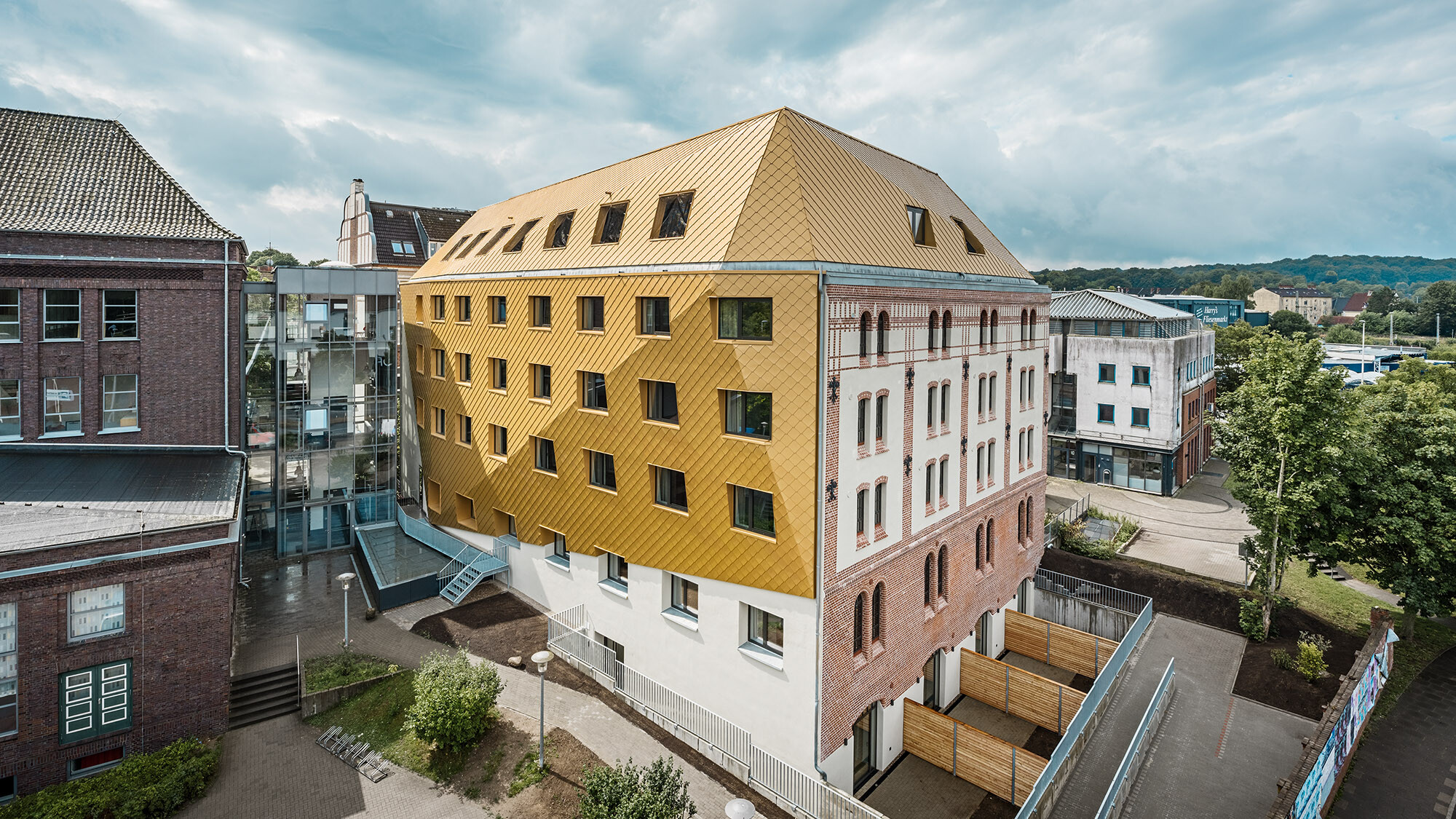 Das neue Studentenwohnheim aus der seitlichen Vogelperspektive, die geknickte Hülle stülpt sich im oberen Bereich über das Gebäude.