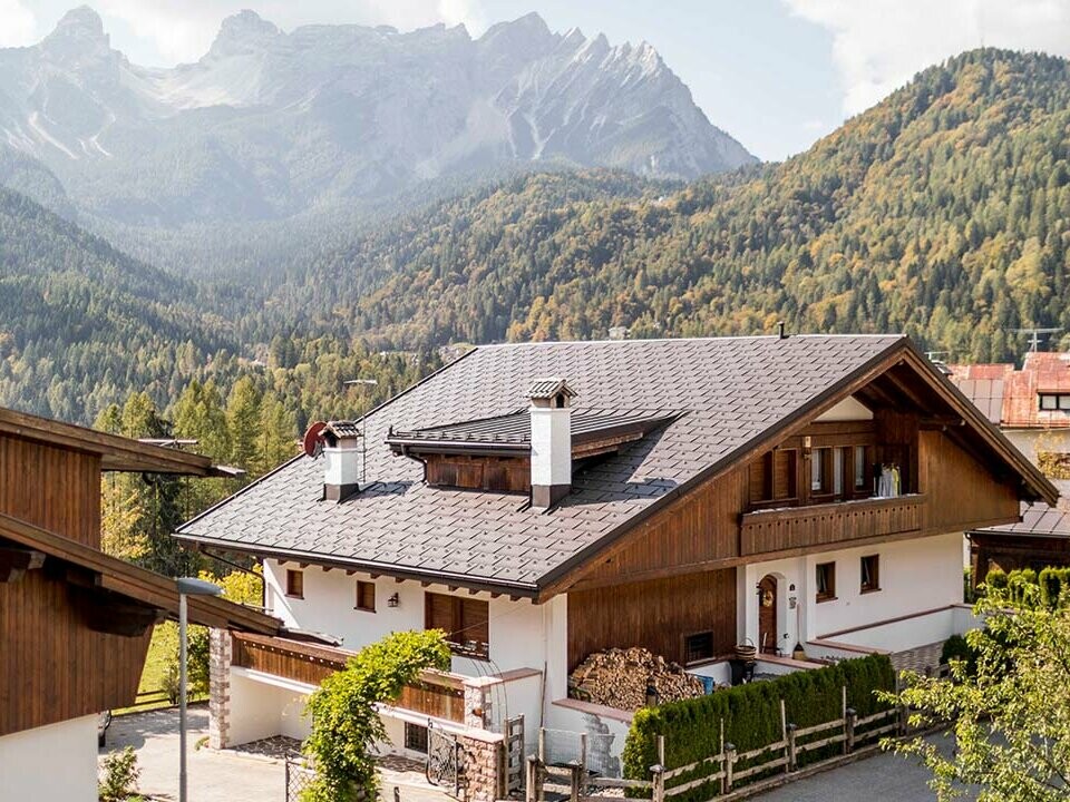 Dieses Wohnhaus in den Dolomiten wurde mit PREFA Dachplatten R.16 in P.10 Nussbraun eingedeckt, das traditionelle Haus liegt inmitten der Berge in Italien