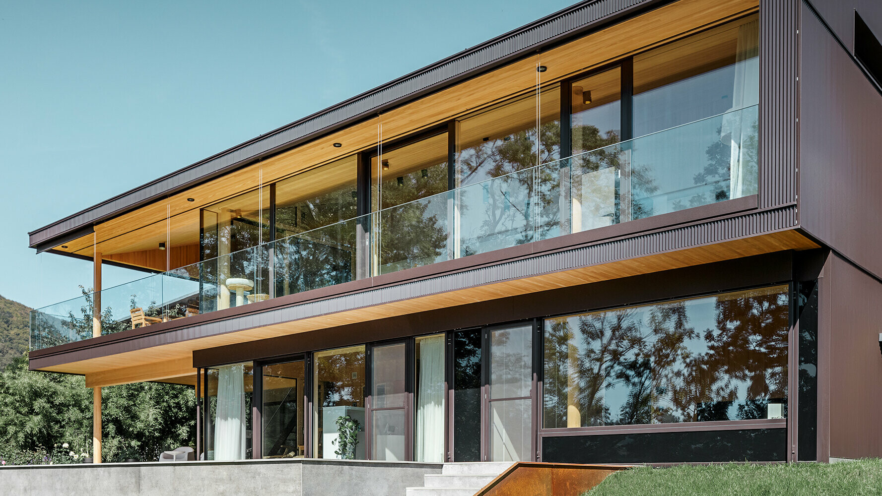 Neues Einfamilienhaus mit großen Glasflächen und brauner Aluminium Fassade