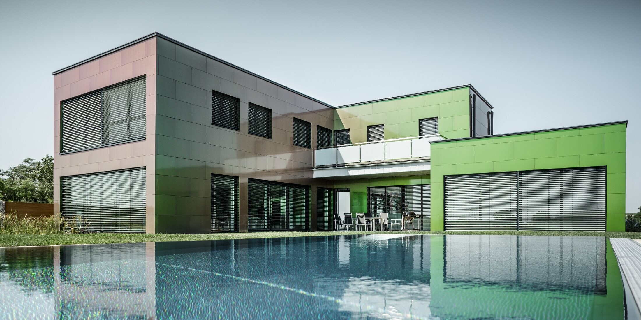 Modernes Einfamilienhaus mit Flachdach uns großem Swimming Pool; Die Fassade ist mit PREFA Aluminium Verbundplatte in der Sonderfarbe Chameleon Spring Lake verkleidet.