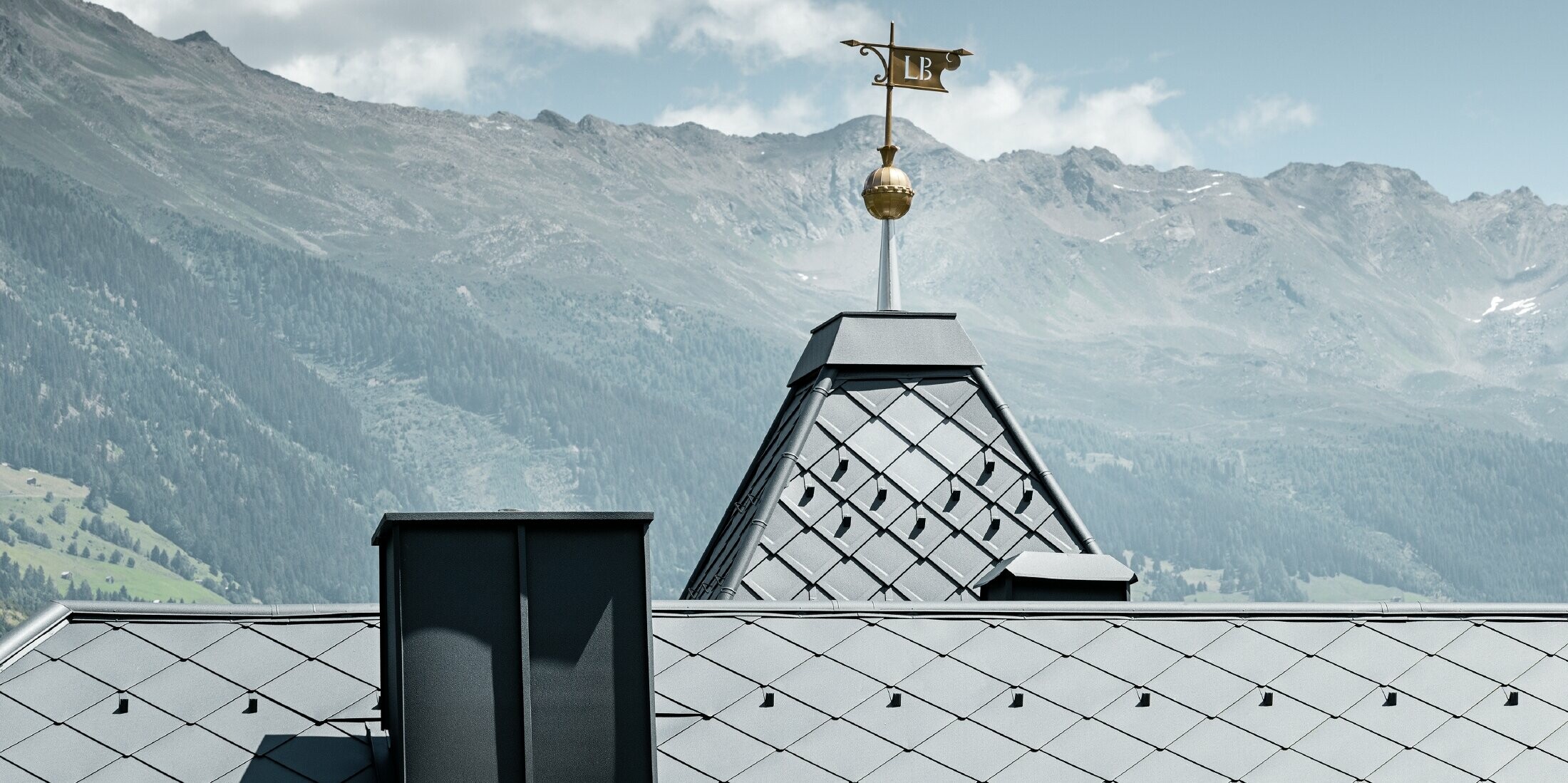 Felsenhaus mit Turm und einem Aluminiumdach in anthrazit mit einer Pizzeria im Erdgeschoss