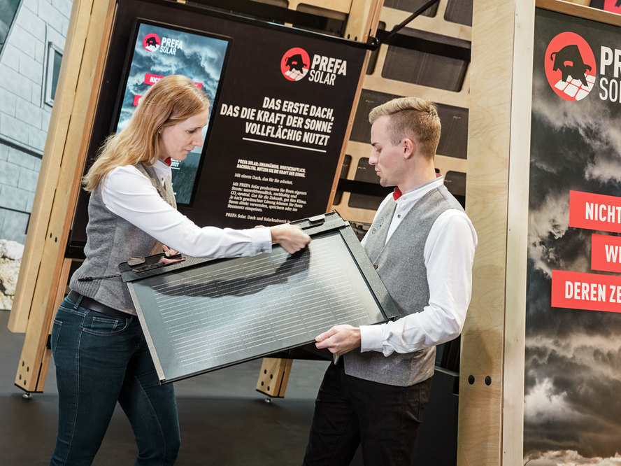 Das Entwicklerteam vor dem Messestand mit einer PREFA Solardachplatte 