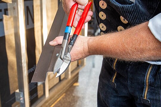 In dieser Detailaufnahme zeigt uns der PREFA Techniker, wie man die Längsstoßüberlappung am unteren Schenkel ca. 15 mm schräg ausklinkt.