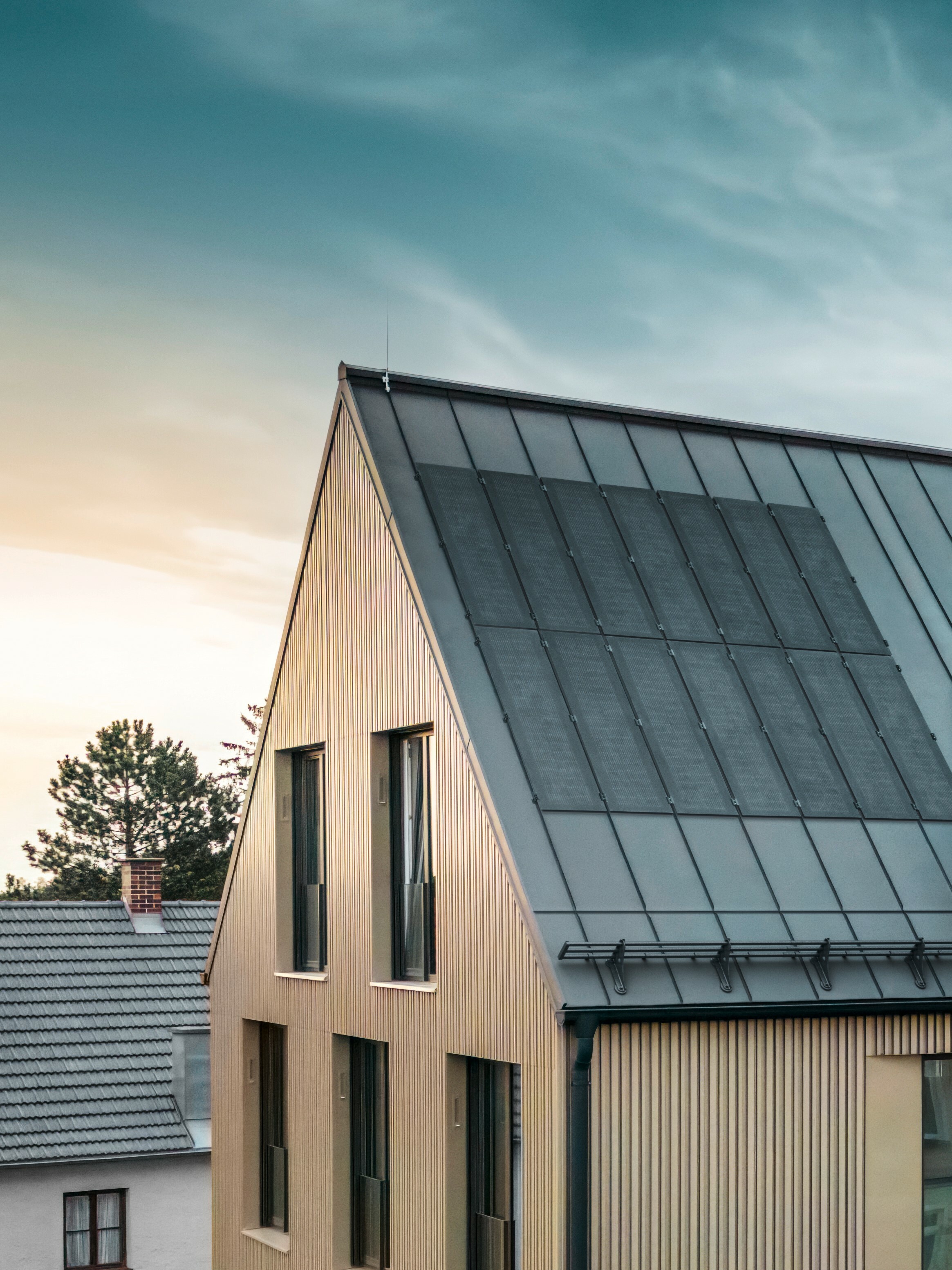 Zu sehen ist ein Gebäude mit bronzener PREFALZ Fassade. Die innovativen PREFALZ Solarmodule mit neuester TOPCon-Zellentechnologie auf dem schwarzgrauen PREFALZ Dach sorgen für eine nachhaltige Energiegewinnung.