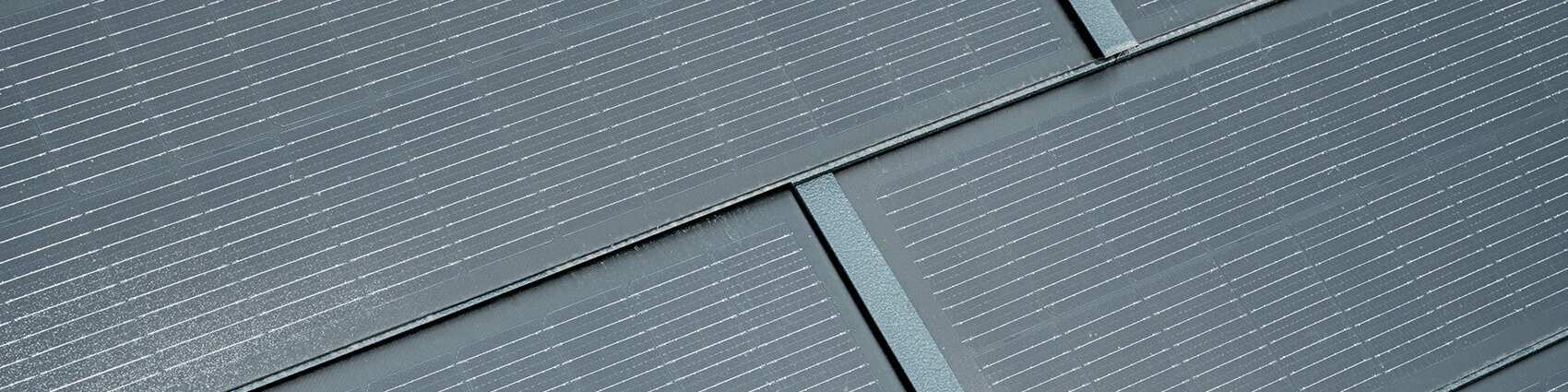 Detailaufnahme der verlegten PREFA Solardachplatte. Die Solardachplatte in der Farbe P.10 Anthrazit wurde mit der Dachplatte R.16 kombiniert. 