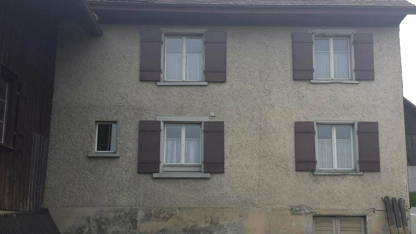 Haus vor der Fassadensanierung mit der PREFA Wandraute, Fenster mit roten Fensterläden