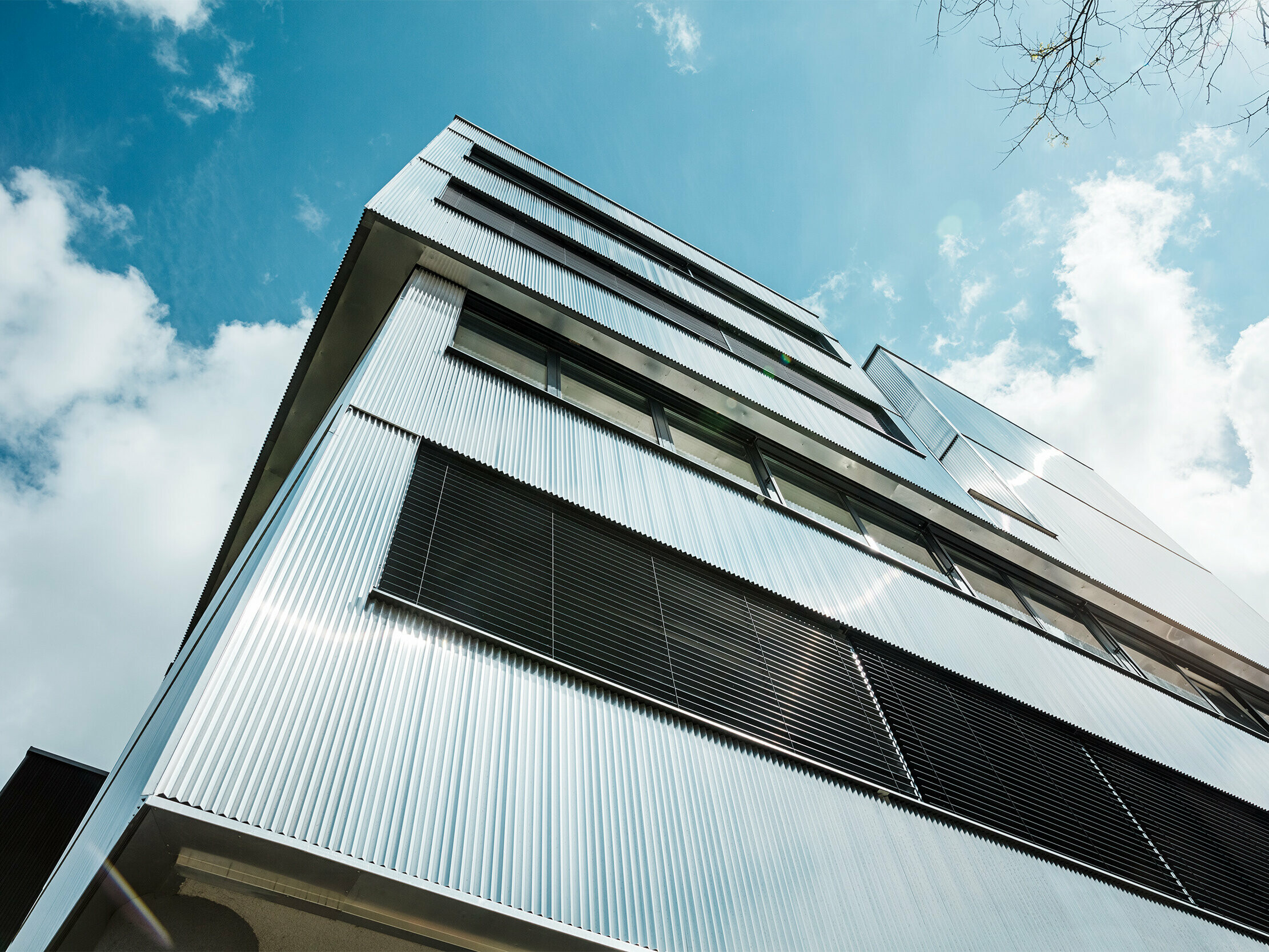 Nahaufnahme der Fassade der Musikschule in Bjevolar mit dem PREFA Zackenprofil. Die Fassade besteht aus einer Kombination von schwarzen und naturblanken Oberflächen, die in der Sonne glänzen und das moderne Design betonen.