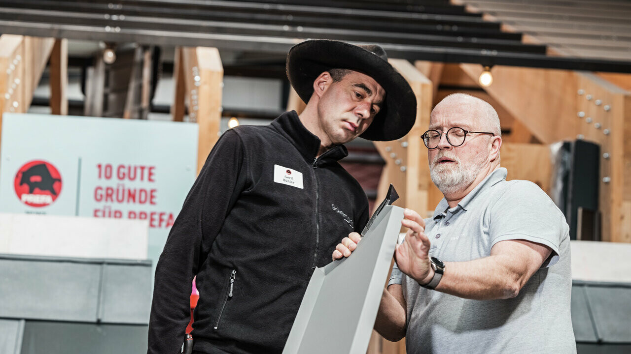 Ein Ausbilder der PREFA Academy zeigt einem Teilnehmer die korrekte Handhabung eines Aluminium-Dachpaneels.