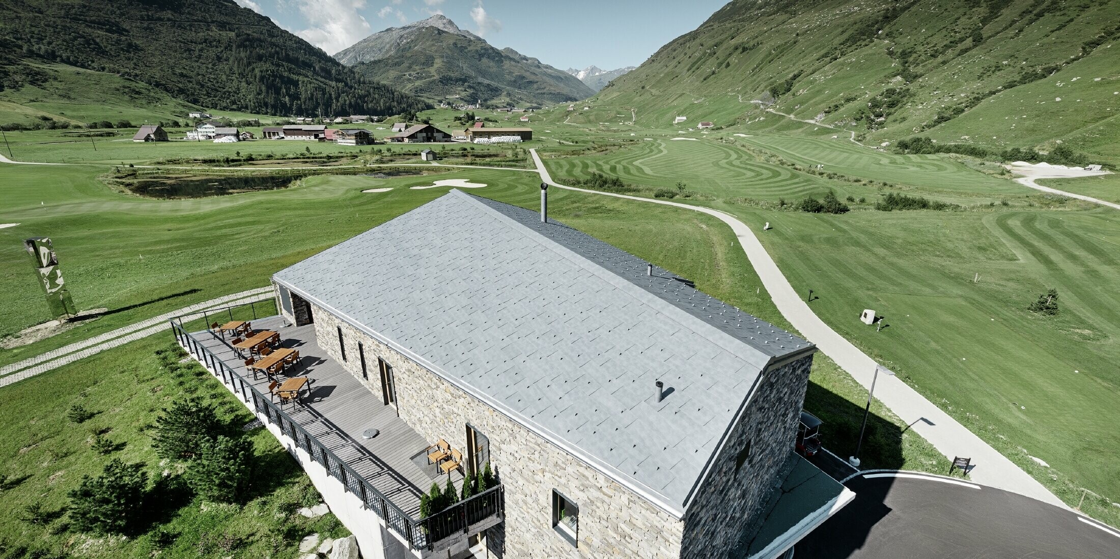 Modernes Club Haus des Golfplatzes in Andermatt mit Steinfassade und PREFA Dachpaneel FX.12 aus Aluminium in steingrau