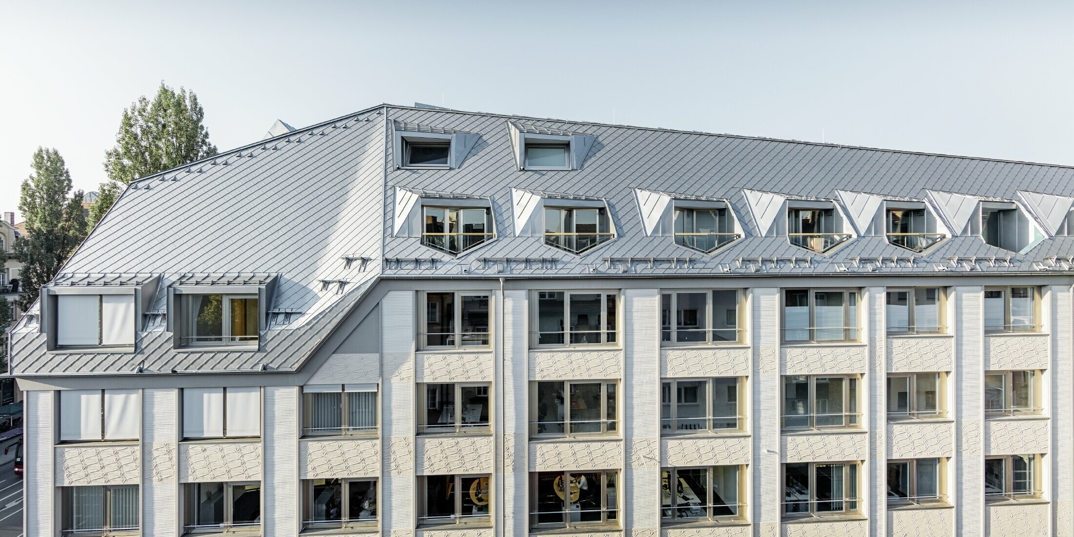 Sanierte Mansardenwohnungen mit großzügigen offenen Galerieebenen eines Wohn- und Geschäftshauses in der Leopoldstraße/Ecke Hohenzollernstraße in München, mit einer Dacheindeckung von PREFA - Dachraute