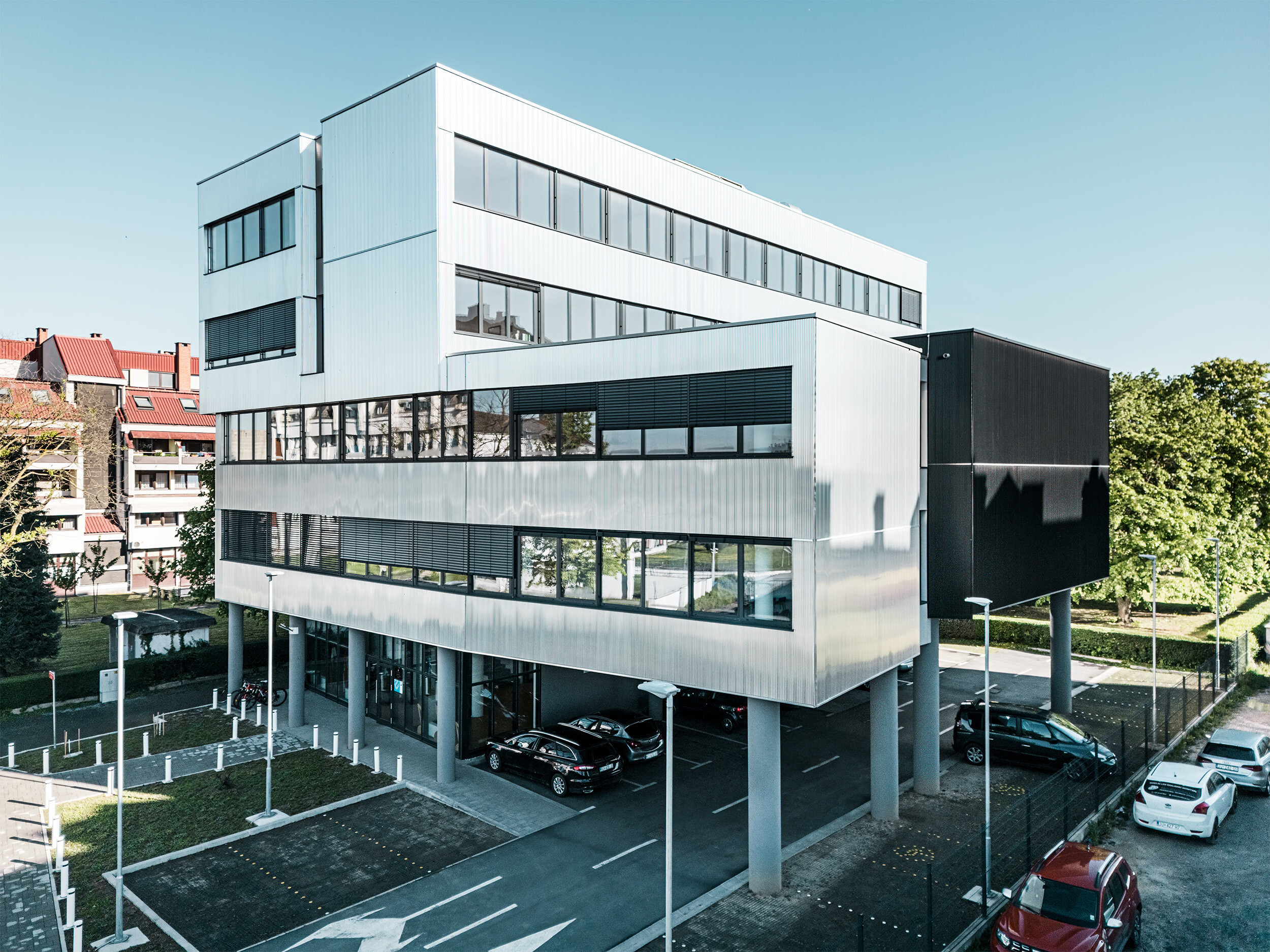 Schräg von unten aufgenommene Perspektive der Musikschule in Bjevolar mit PREFA Zackenprofilfassade. Die Kombination aus schwarzen und aluminiumblanken Fassadenelementen sowie großen Glasfenstern verleiht dem Gebäude einen modernen und zeitgemäßen Stil.