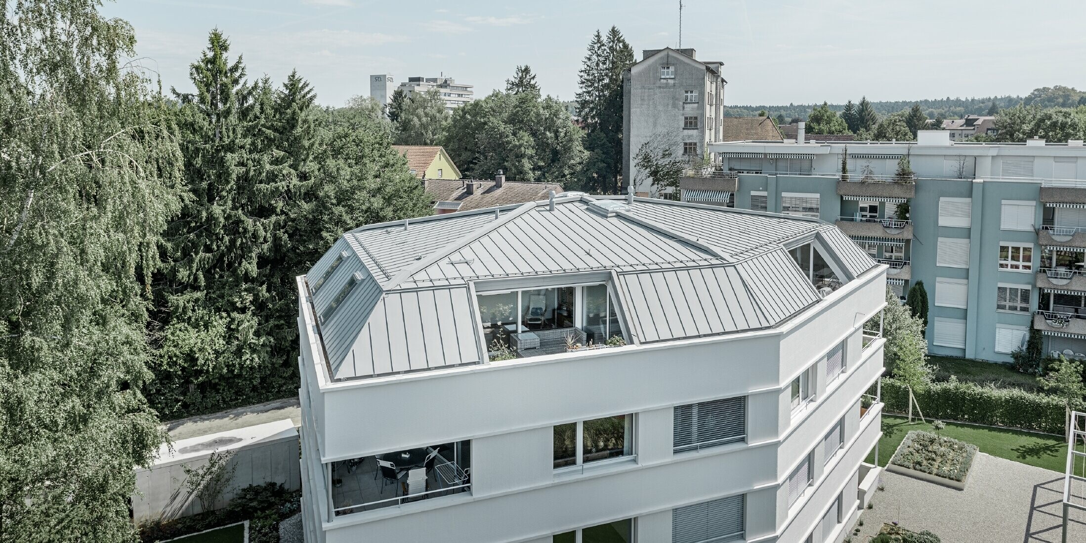 Dach eines Mehrparteienhauses eingedeckt mit dem PREFA Prefalz in Patina grau mit  Loggia.