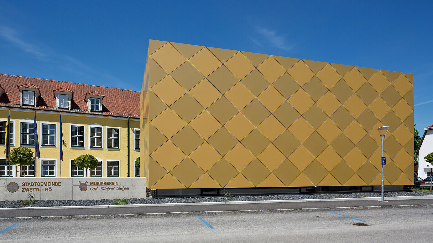 Blick von der Straße auf den Musikverein Zwettl. Das quaderförmige Gebäude ist vollständig mit PREFA Aluminium Verbundplatten umhüllt. 