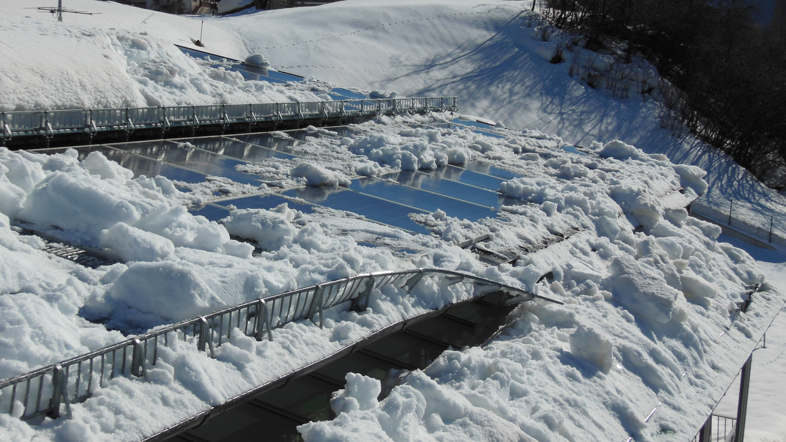 Das Bild zeigt ein defektes Schneefangsystem in einer weißen Winterlandschaft. Ein schneebedecktes Dach mit montierten Schneerechen sollte Schäden durch herabfallende Dachlawinen verhindern. Durch das instabile System können Personenschäden nicht ausgeschlossen werden. Mit einem hochwertigen Schneefangsystem von PREFA können Schäden dieser Art vermieden werden.