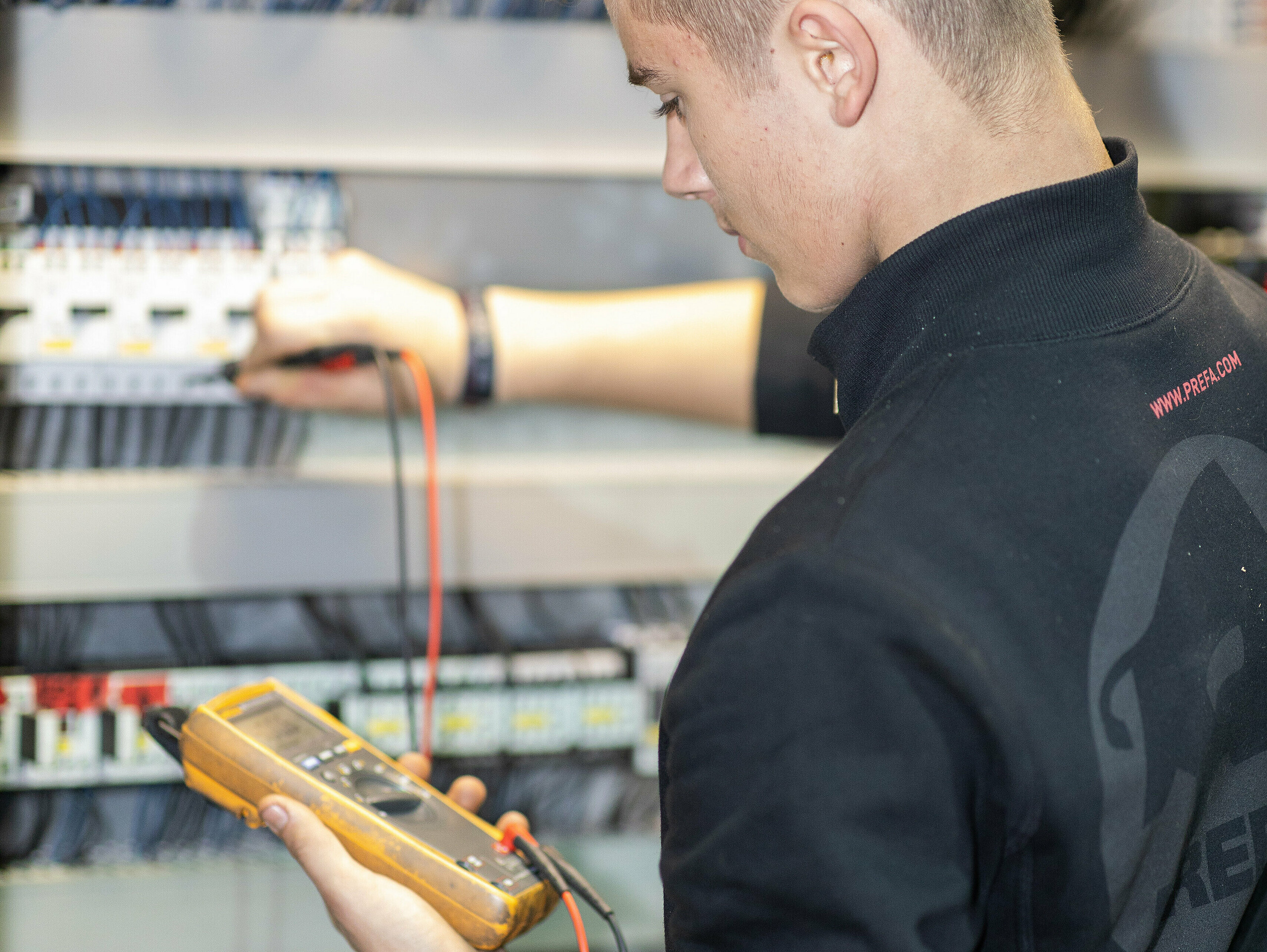 PREFA Lehrling für Elektrotechnik vor dem Schaltkasten.