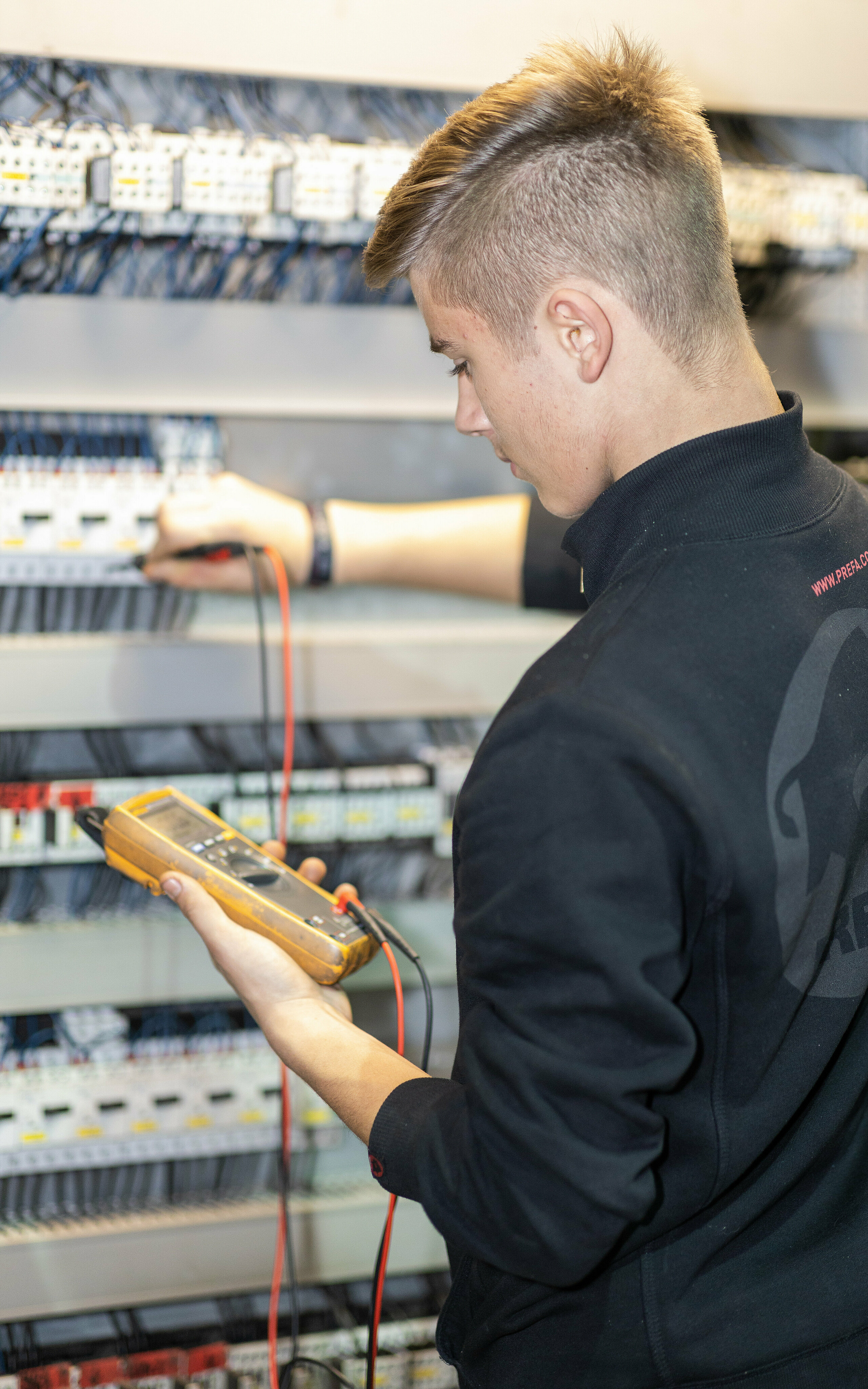 PREFA Lehrling für Elektrotechnik vor dem Schaltkasten.