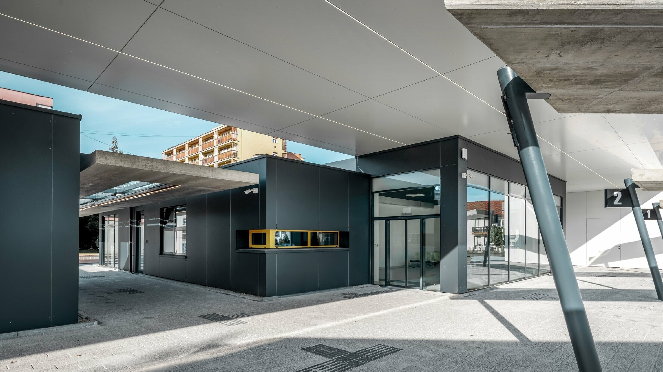 Überdachter Bereich des Busbahnhofs Lenti; Die Untersicht der Überdachung ist mit PREFABOND Verbundplatte in Reinweiß verkleidet, die Fassadenelemente beim Eingangsbereich in P.10 Anthrazit.