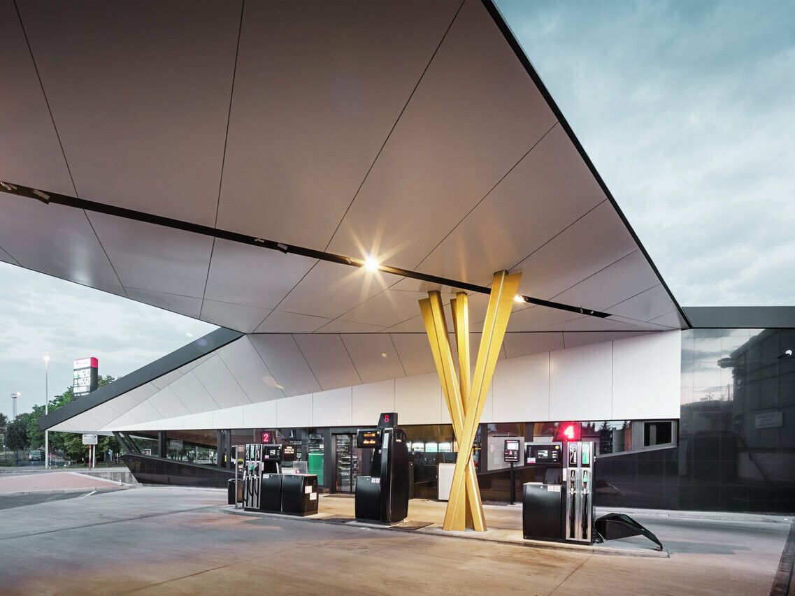 Eine beleuchtete Tankstelle in Prag (Tschechien), verkleidet mit PREFABOND Verbundplatte in Schwarzgrau und Reinweiß.