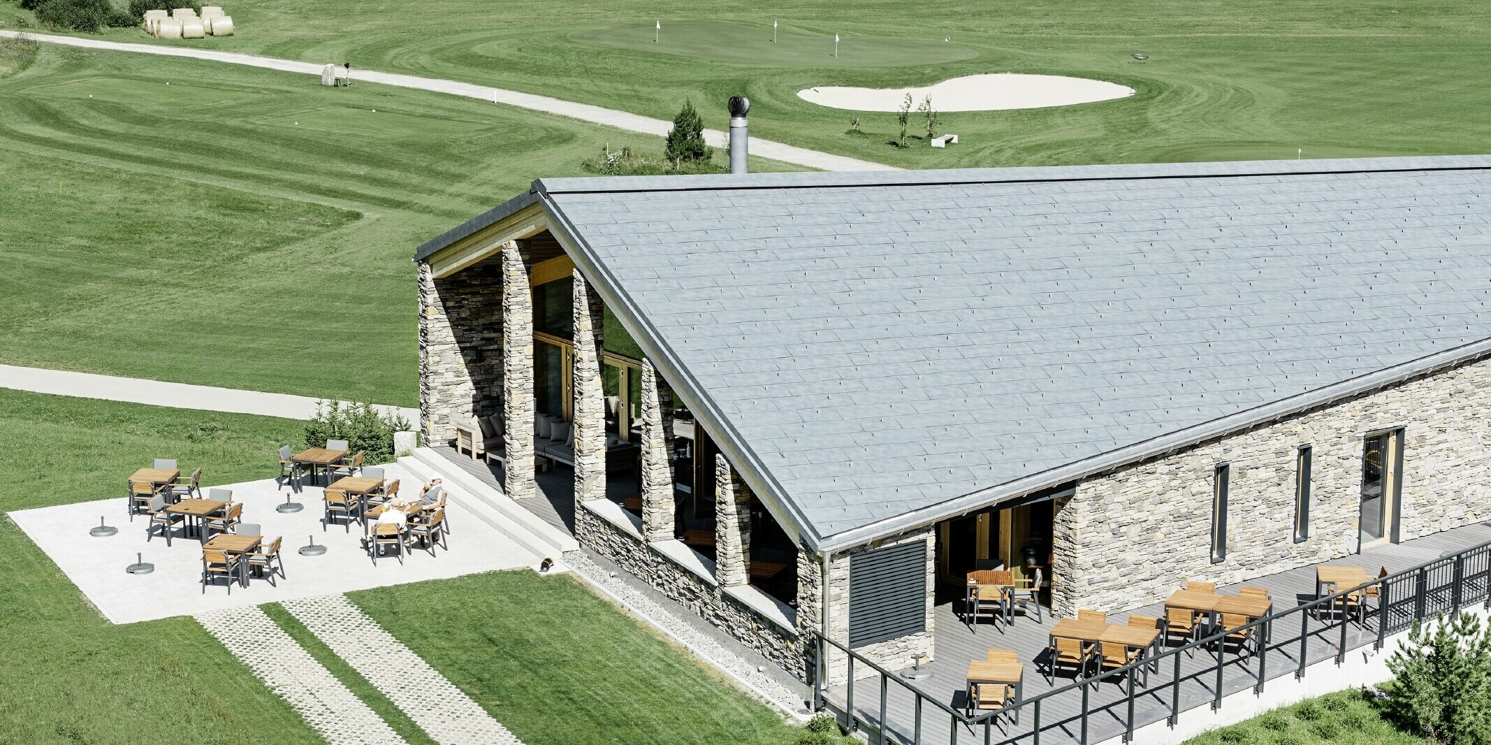 Modernes Club Haus des Golfplatzes in Andermatt mit Steinfassade und PREFA Dachpaneel FX.12 aus Aluminium in steingrau