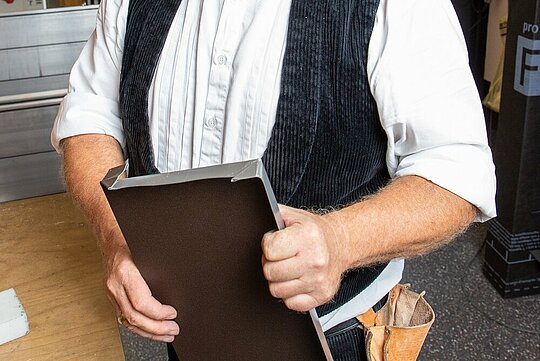 Der PREFA Techniker hält die selbst erstelle Fensterbank mit wasserdichter Quetschfalte in der Hand.