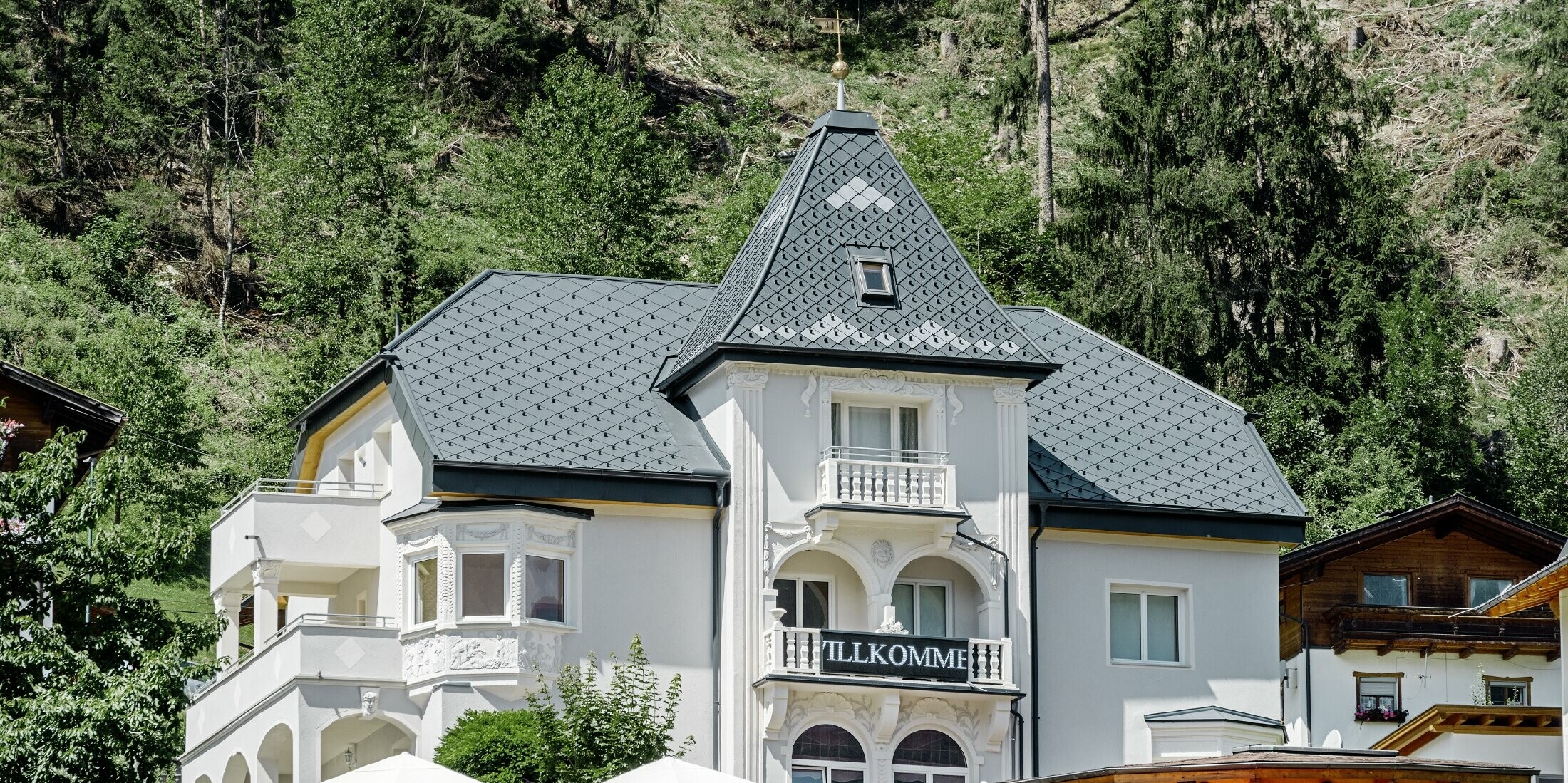 Felsenhaus mit Turm und einem Aluminiumdach in anthrazit mit einer Pizzeria im Erdgeschoss