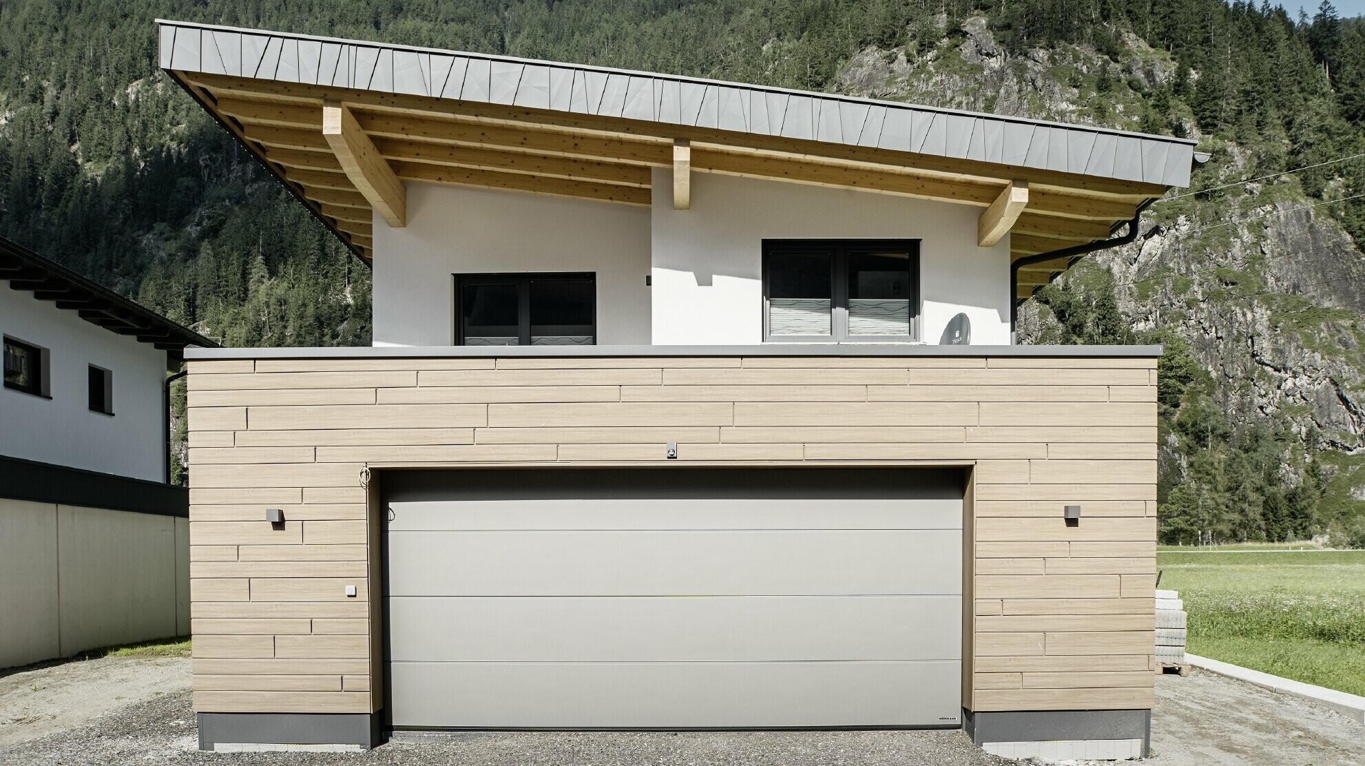 Moderner Neubau mit Pultdach und individueller Ortgangverblechung, Garage mit Flachdach und Alu-Fassade in Walnuss braun von PREFA. Die Sidings wurden horizontal verlegt und mit unterschiedlichen Baubreiten.