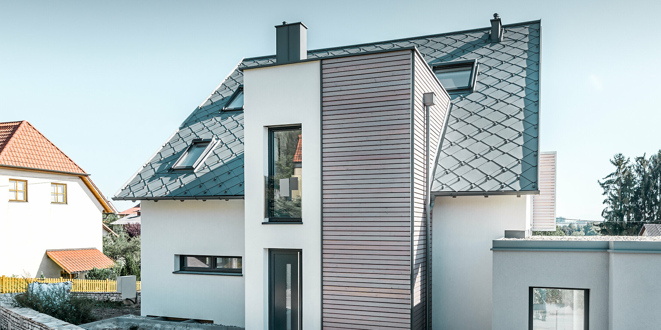 Das Einfamilienhaus mit Satteldach in Leodonding wurde rundum saniert. Die Dachfläche wurde neu mit der PREFA Dachraute 44 × 44 in Hellgrau inklusive Schneestoppern eingedeckt. Die Rinne ist die Hängerinne von PREFA, ebenfalls in Hellgrau. 