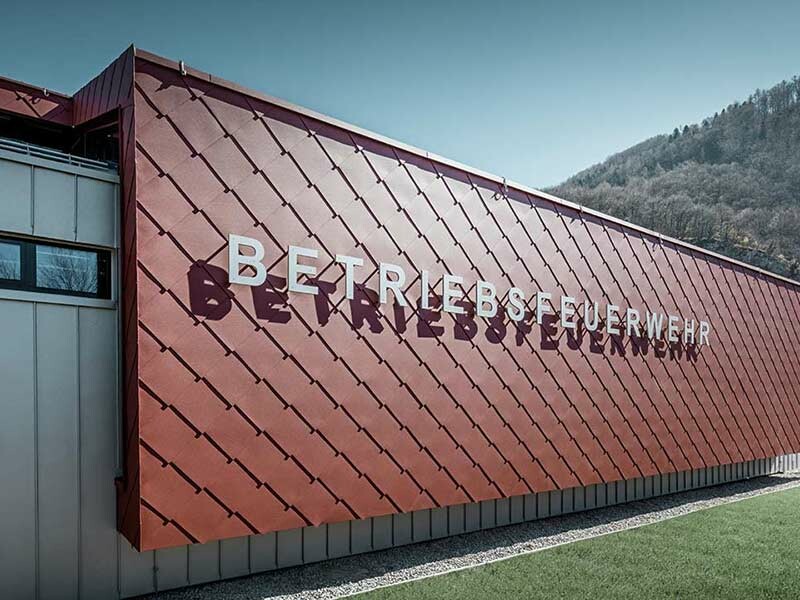 rote Alufassade mit großflächigen Rauten und dem Schriftzug "Betriebsfeuerwehr", verkleidet mit der PREFA Aluminium Wandraute 44 × 44