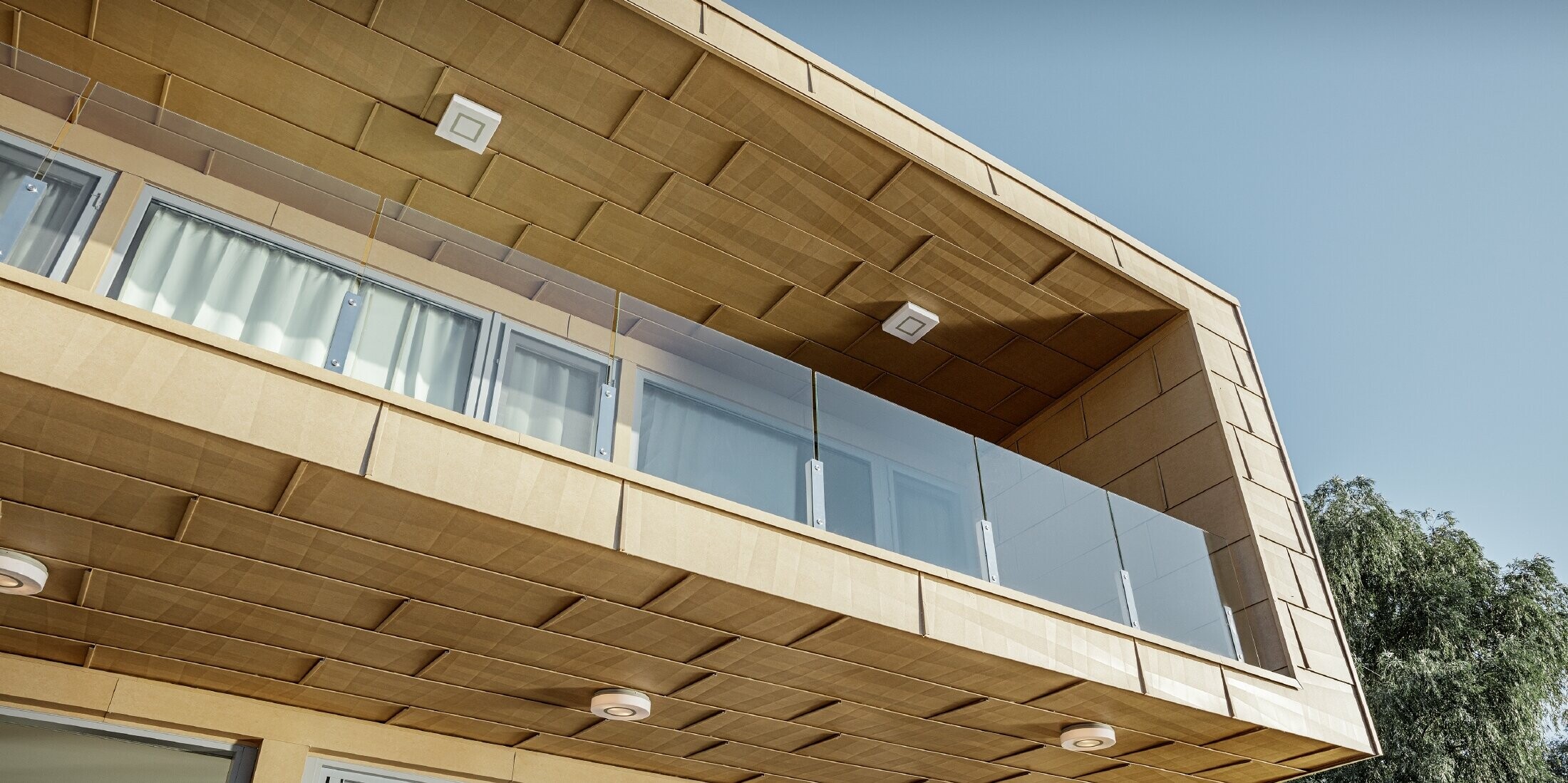 modernes Wochenendhaus mit Flachdach und großen Fensterflächen am See mit einer gekanteten Aluminiumfassade in sandbraun