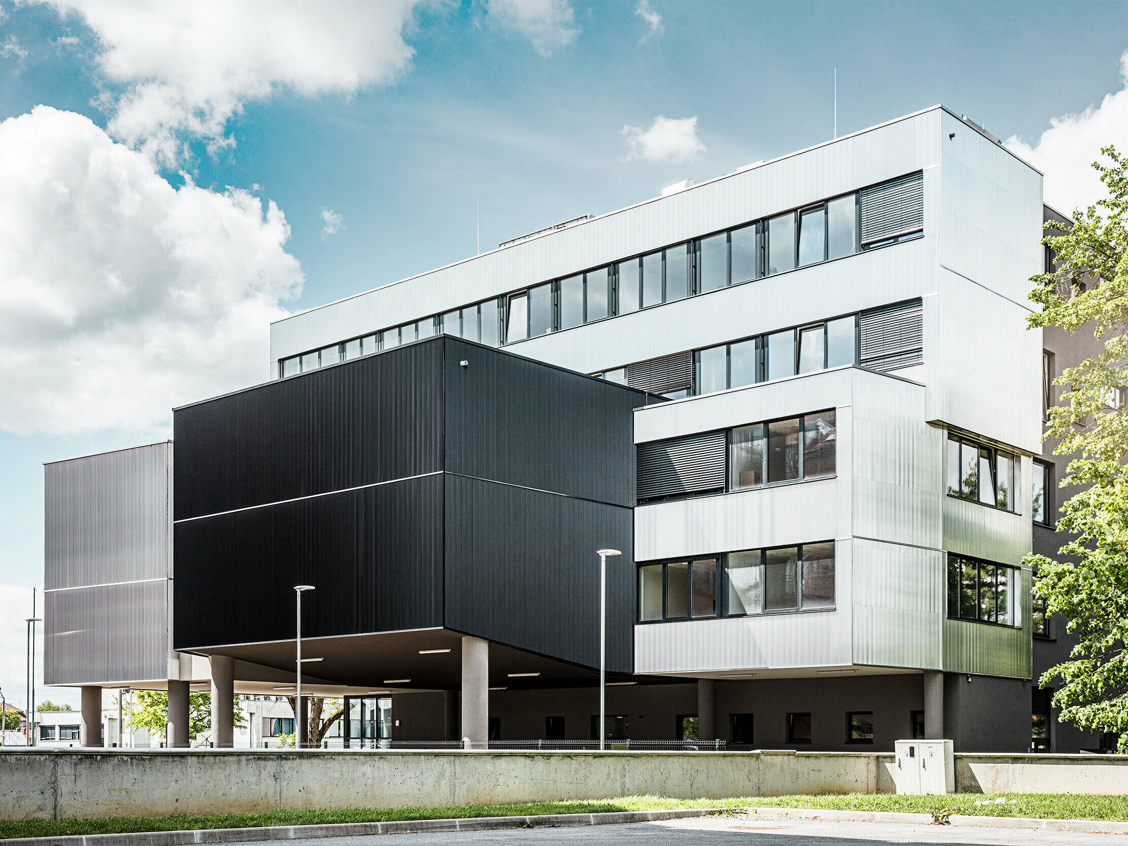 Seitenansicht der Musikschule in Bjevolar mit einer modernen PREFA Fassade im Zackenprofil. Die Fassade ist in Schwarz und aluminiumblank gehalten, und die geometrischen Formen sorgen für ein markantes, minimalistisches Design.