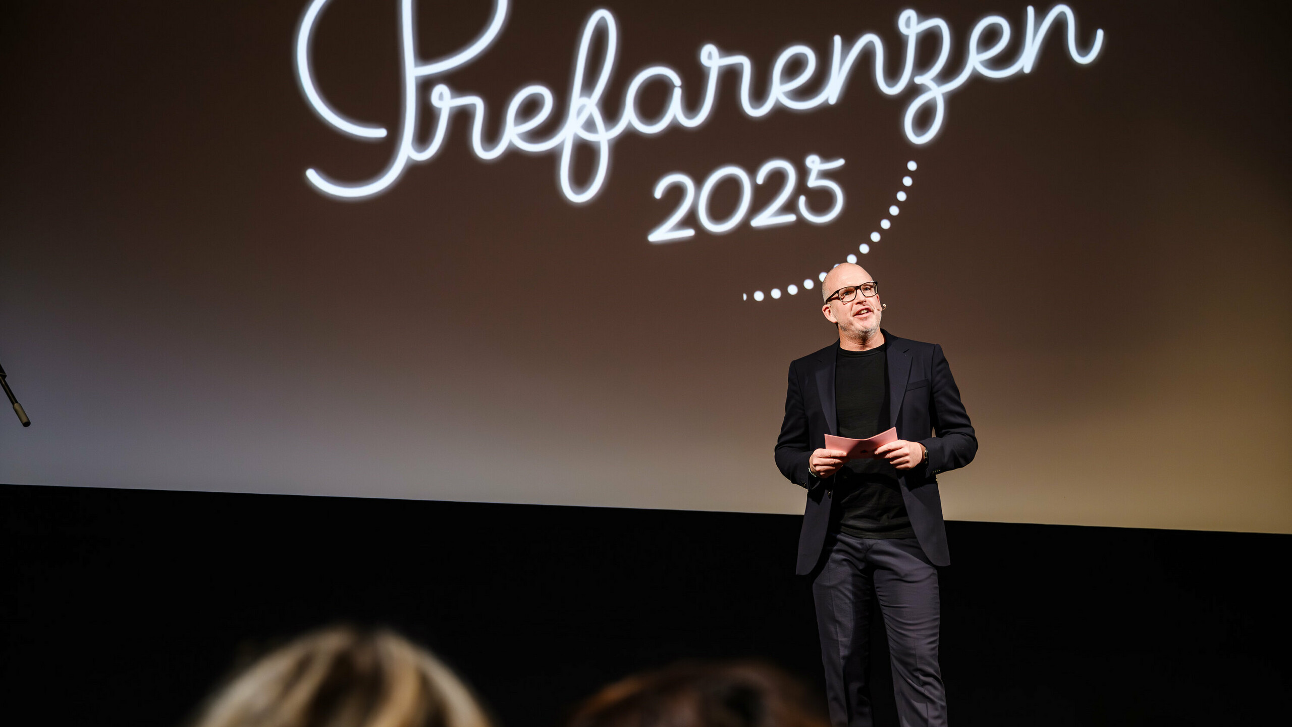 Jürgen Jungmair, Marketingleiter von PREFA, hält eine Rede bei der PREFARENZEN-Premiere 2025 im Stadtkino Wien. Im Hintergrund ist das Logo der Veranstaltung ‚Prefarenzen 2025‘ zu sehen.