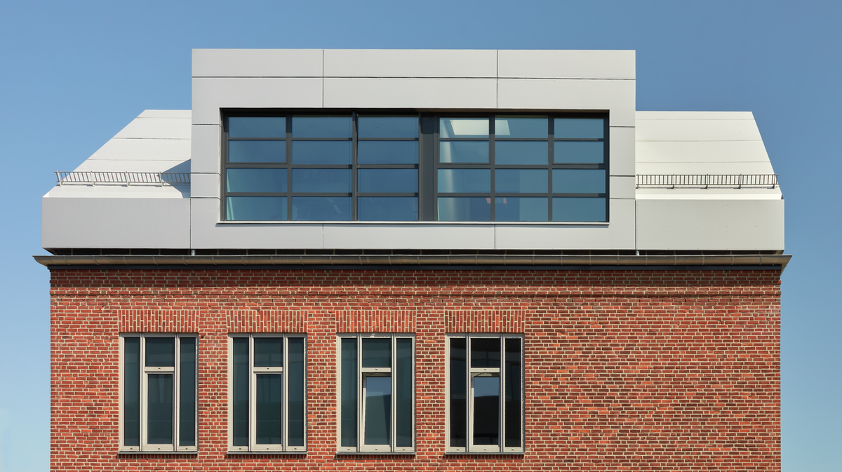 In der Abbildung sind die PREFABOND Aluminium Verbundplatten in Silbermetallic und Anthrazit zu sehen. Diese wurden auf das Backsteingebäude einsteineins im Wissenschaftspark in Kiel montiert.