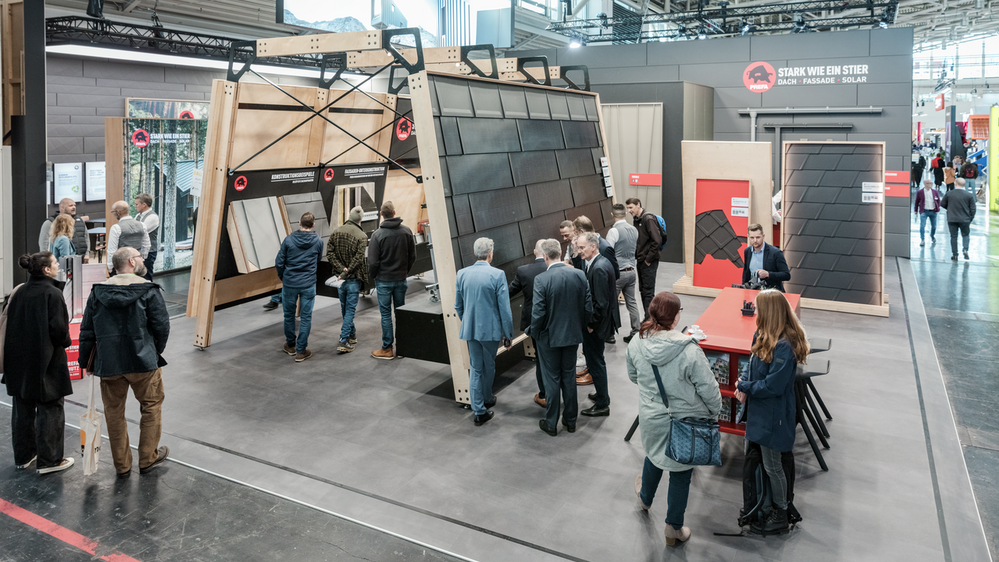 Übersicht auf die beiden Messestände der PREFA auf der BAU Messe 2025 in München. An dem Messestand können Besucher die neuesten Dach- und Fassadenlösungen sowie das Solarmontagesystem PREVARIO 3.S erkunden. Ausgestellte Produkte, wie Aluminium-Dachplatten und Fassadenpaneele, sind auf großen Rahmen präsentiert.