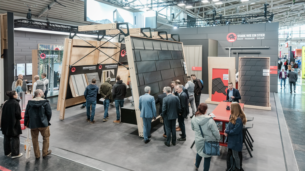 Übersicht auf die beiden Messestände der PREFA auf der BAU Messe 2025 in München. An dem Messestand können Besucher die neuesten Dach- und Fassadenlösungen sowie das Solarmontagesystem PREVARIO 3.S erkunden. Ausgestellte Produkte, wie Aluminium-Dachplatten und Fassadenpaneele, sind auf großen Rahmen präsentiert.